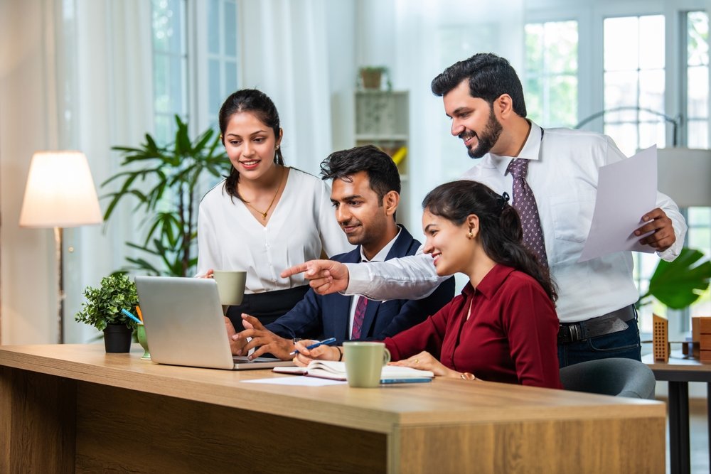 Indian,asian,young,business,professionals,using,laptop,on,desk,discussing